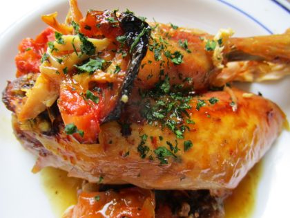 Pollo asado con su piel crujiente y tomates, todo ello envuelto en papel.