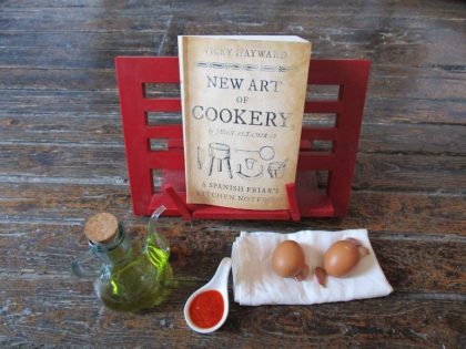 Esperando acción en la cocina! El libro de bolsillo de “New Art of Cookery, A Spanish Friar’s Kitchen Notebook”, abierto y con ingredientes.